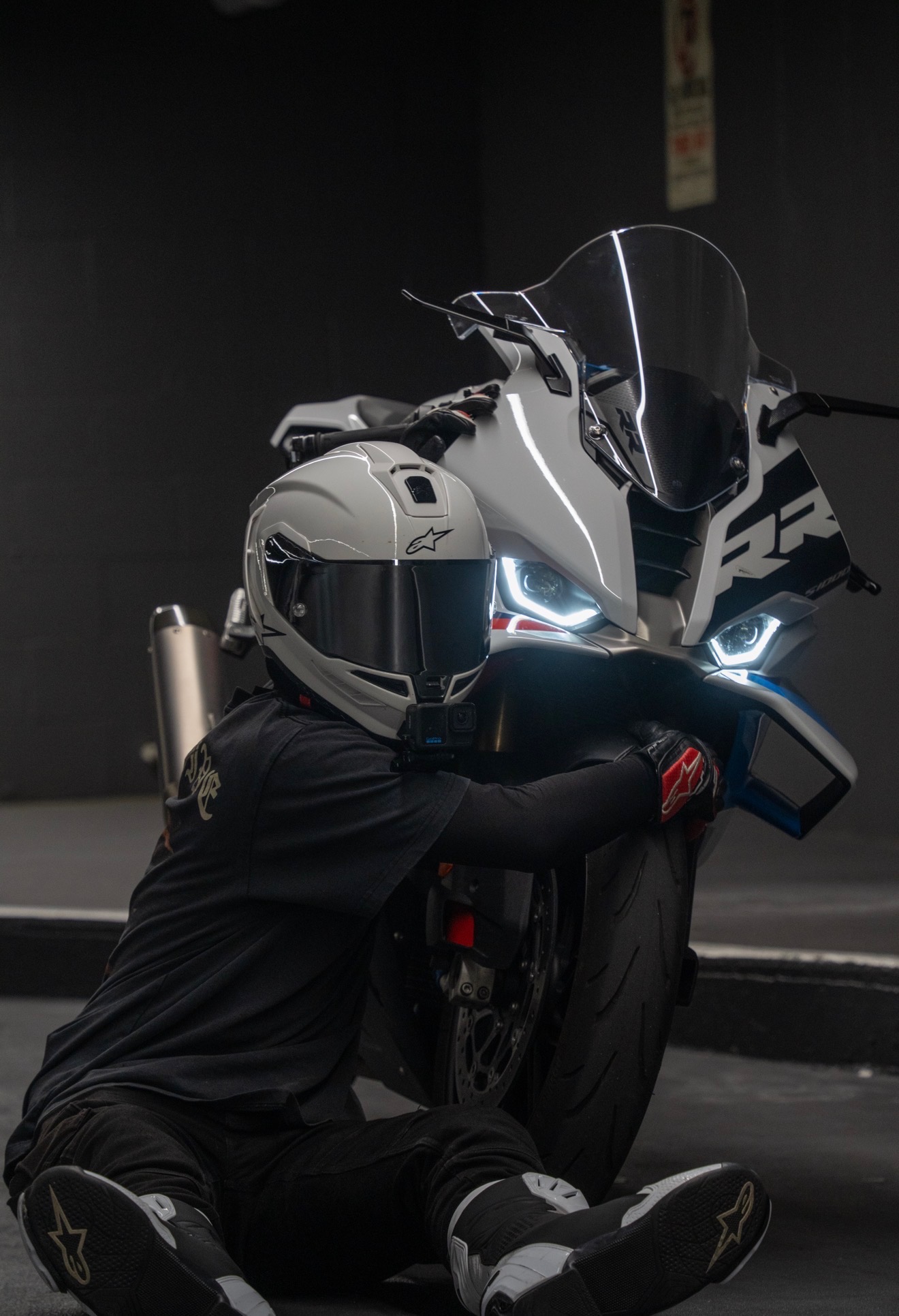 Blaze leaning over the tail of his BMW S1000RR, helmet reflecting the headlights.