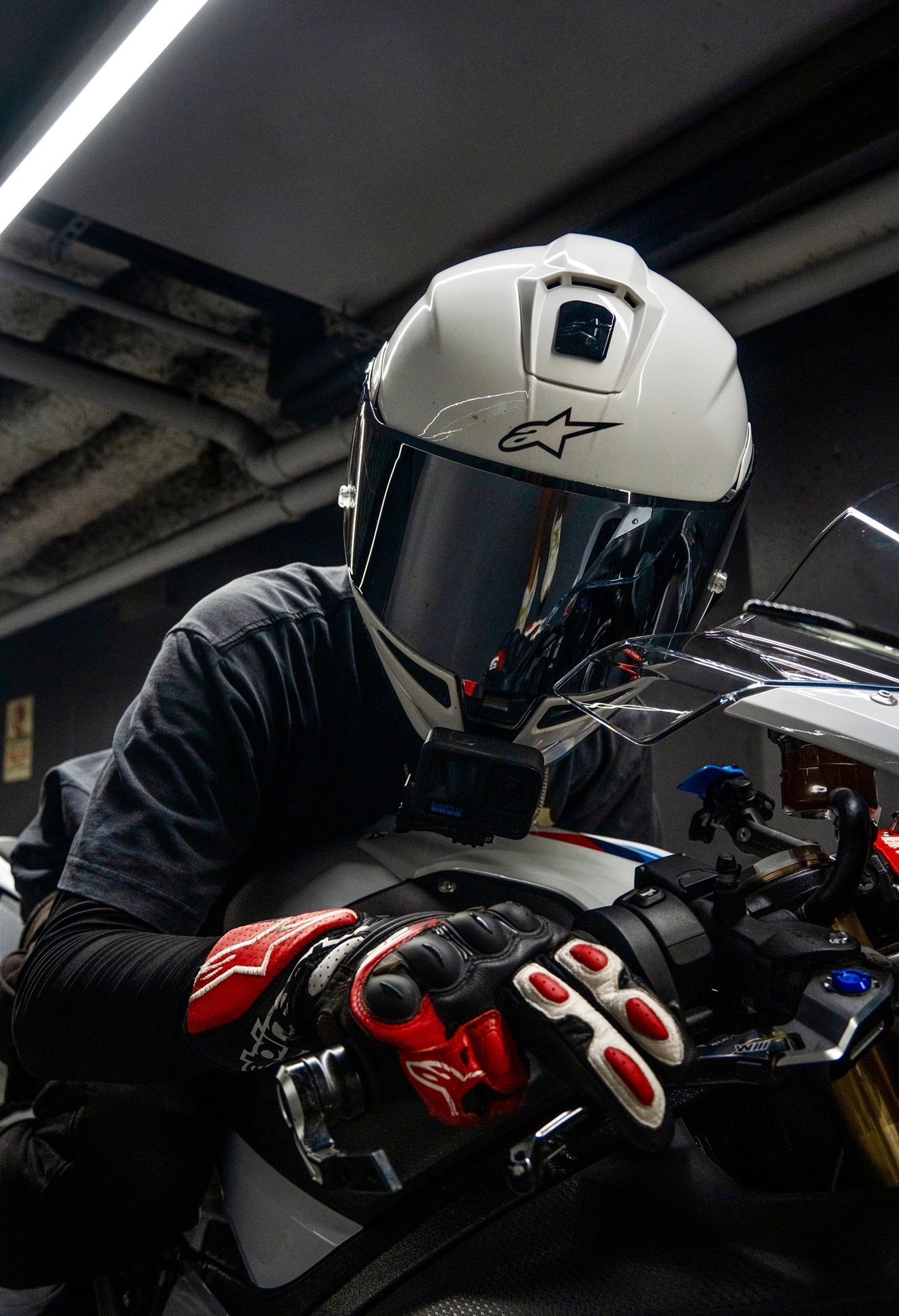 Close-up of Blaze's mirrored helmet visor reflecting the garage, preparing for the next ride.