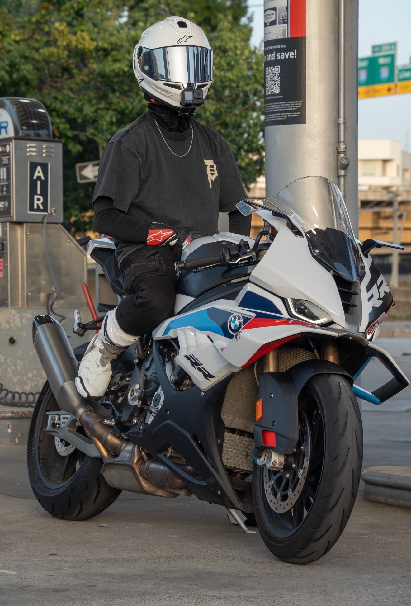 Blaze seated on his BMW S1000RR facing the camera at a gas station.