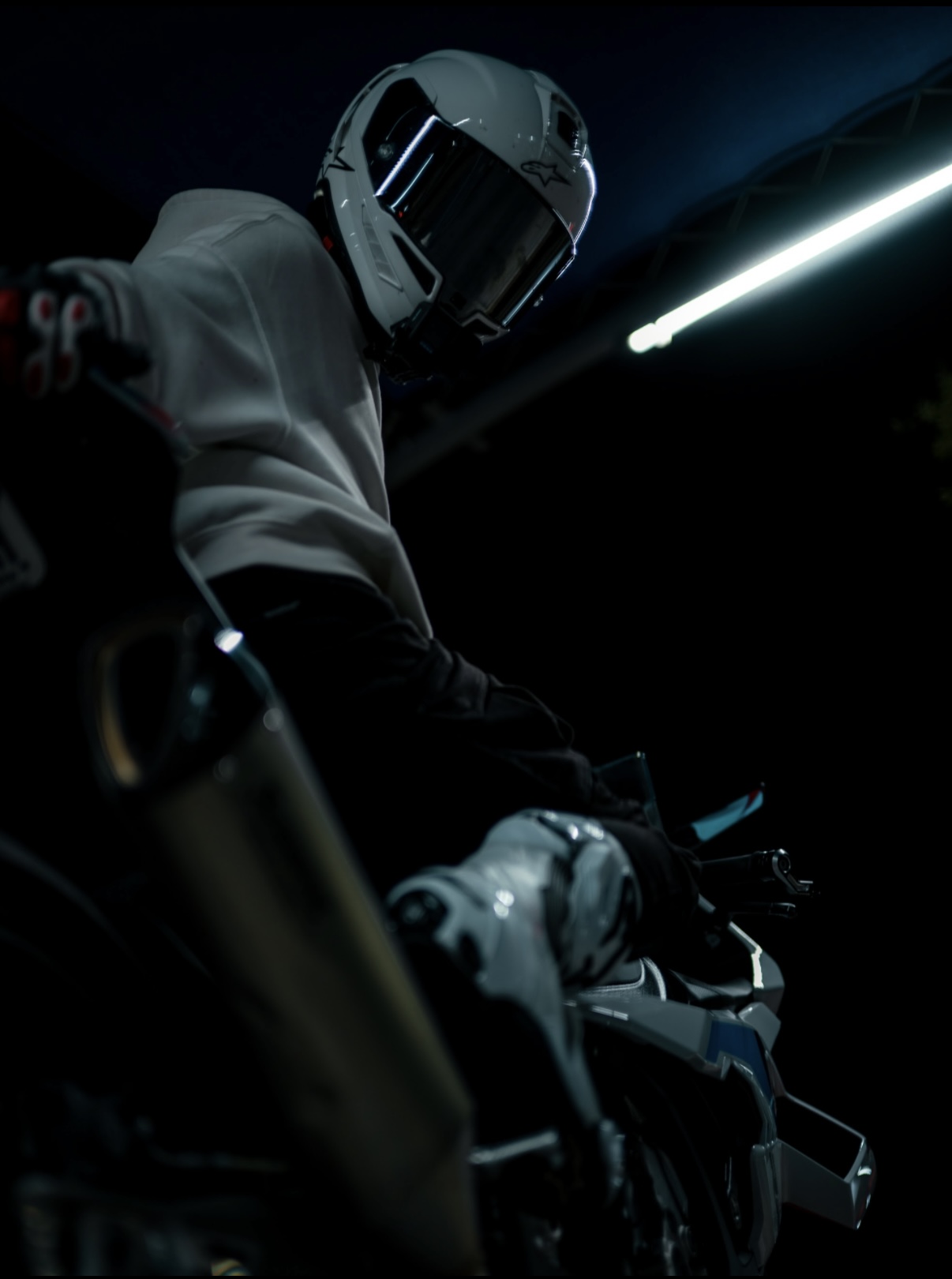 Blaze leaned forward over his BMW S1000RR, motion blur in the frame under garage lighting.