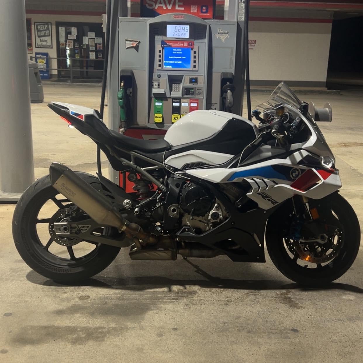 Blaze's BMW S1000RR parked at a gas pump, side profile, aftermarket exhaust visible.